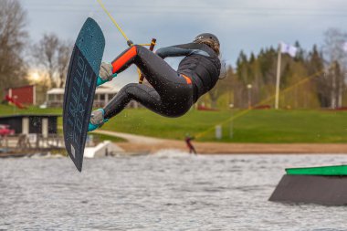 Fagersta, İsveç - Maj 07, 2020: Genç bir kız Wakeboard 'da aşırı atlıyor, etrafta bir sürü sıçrama oluyor, bir wakeboard' un üstünde baş aşağı..