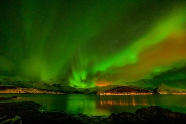 Norveç doğası, kuzey ışıkları, gökyüzünde birçok bulut ve yıldız bulunan Aurora borealis Avrupa 'nın kuzeyindeki fiyort dağları üzerinde, Lofoten adaları, Norveç, uzun kepenk hızı.