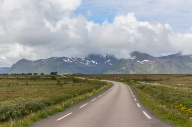 bulutlu gökyüzünün altında Norveç dağları arasında düz ve yalnız yol, seçici odaklanma