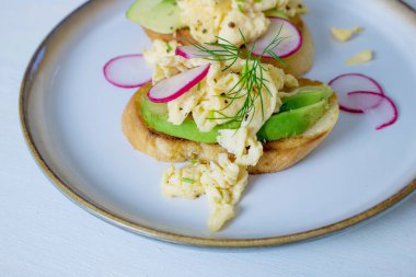 Avokado tostu, çırpılmış yumurta ve diğer kahvaltılık eşyalar.