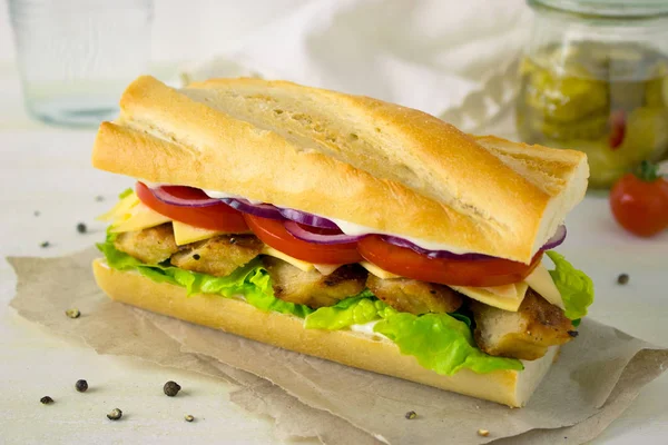 Food photography of a baguette sandwich with grilled chicken, tomatoes and red onions