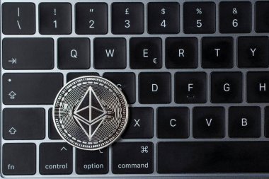 Ethereum kripto para birimi, şifreli para birimi. Dizüstü bilgisayar klavyesinde altın bir Ethereum sembolü olan gümüş Ethereum sikkesi. Fiziksel metal gümüş. Dünya çapında sanal internet parası.