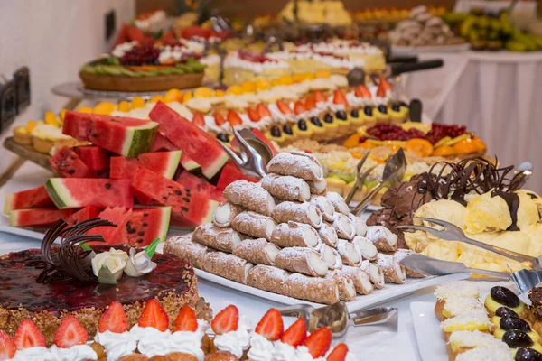 Buffet con dolci. frutta e altri dolci sul tavolo da dessert. Righe di dolci dall'aspetto gustoso in bellissimi arrangiamenti. Dolci sul tavolo del banchetto - foto scattata durante l'evento di catering — Foto Stock