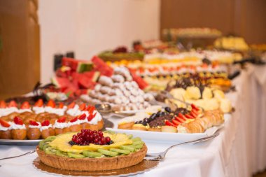 Şekerli büfe. Tatlı masasında meyveler ve diğer tatlılar. Hoş görünümlü tatlı sıraları güzel düzenlemeler içinde. Şölen masasında şekerler - yemek etkinliği sırasında çekilmiş fotoğraflar