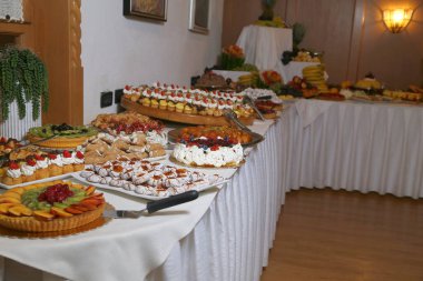 Şekerli büfe. Tatlı masasında meyveler ve diğer tatlılar. Hoş görünümlü tatlı sıraları güzel düzenlemeler içinde. Şölen masasında şekerler - yemek etkinliği sırasında çekilmiş fotoğraflar