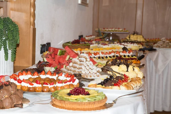 Buffet con dolci. frutta e altri dolci sul tavolo da dessert. Righe di dolci dall'aspetto gustoso in bellissimi arrangiamenti. Dolci sul tavolo del banchetto - foto scattata durante l'evento di catering — Foto Stock