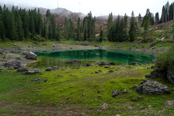 Malebné vrcholky Dolomitských hor v odrazu křišťálově čistého rybníka obklopeného jehličnatým lesem. Lake of Caresse v Itálii. Scénická místa a slavné turistické destinace. Prvotní povaha — Stock fotografie