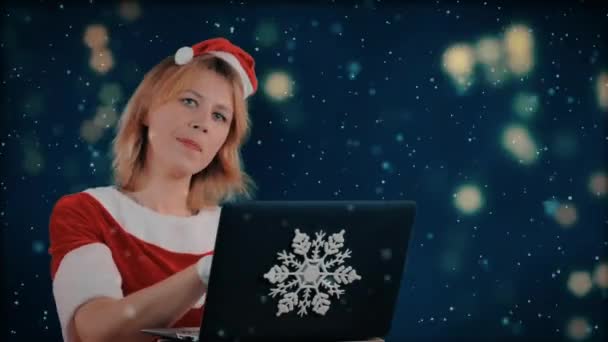 サンタクロースの格好をした女の子は ノートパソコンにハッピーニューイヤーを入力しています アニメーションの背景 背景のライト 雪が降る — ストック動画
