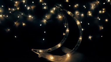 Noel ağacı çelengi gece gökyüzü gibi parıldıyor. Ay yakında yükselecek. Gece gökyüzü ya da Noel çerçevesi şeklinde ışıklar..