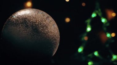 Noel kar küresi animasyonu. Arka planda bir Noel ağacı parlıyor.
