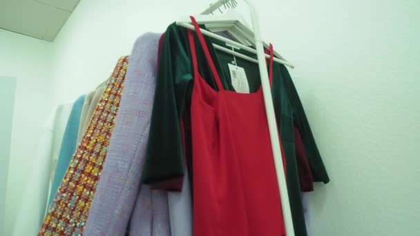 Coleccionable, ropa de diseño cuelga de perchas blancas. En colores lila . — Vídeo de stock