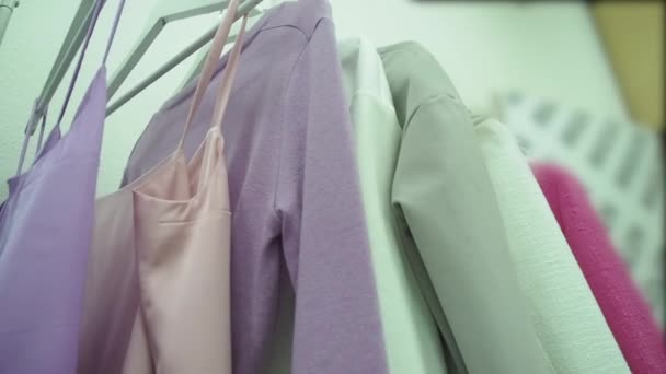 Συλλεκτικά, ρούχα σχεδιαστών κρέμονται σε άσπρες κρεμάστρες. Σε λιλά χρώματα. — Αρχείο Βίντεο