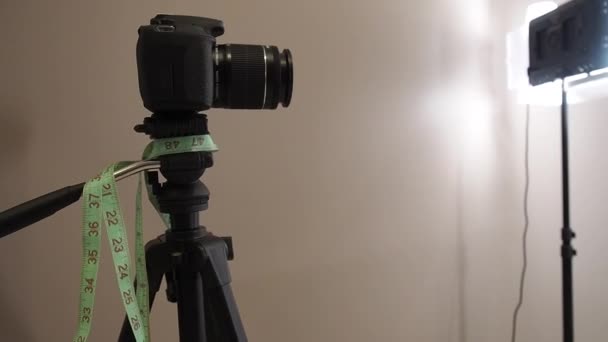 カメラは写真スタジオの三脚の上にあります。三脚の上に腰メートルを掛け. — ストック動画