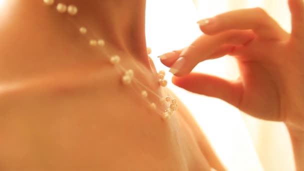 Ruka mladé dívky upravuje náhrdelník z perel. — Stock video