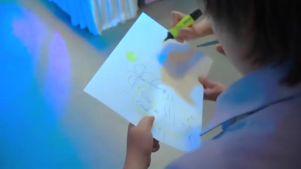 Een man en een vrouw tekenen op een blad van Whatman in neon licht. — Stockvideo