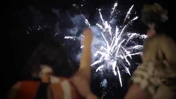 Las mujeres miran el saludo y saludan con las manos. Amigos de pie y ver los fuegos artificiales de la noche . — Vídeos de Stock