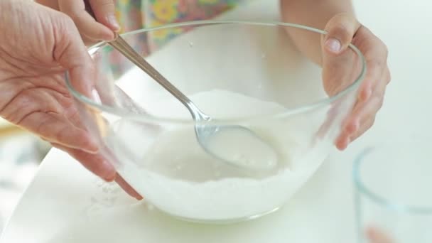 Deux petites filles avec leur mère préparent le petit déjeuner le matin dans la cuisine. Ils mélangent la pâte à crêpes . — Video