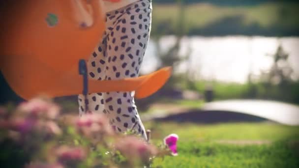 Op een zonnige dag geeft een meisje bloemen water uit een gieter.. — Stockvideo