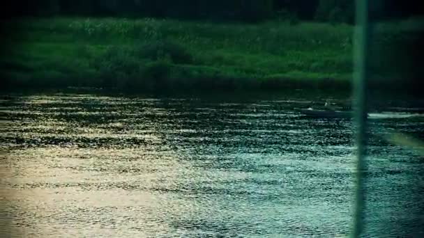 二人の漁師が小さな川の夕日でボートに乗って航海しています. — ストック動画