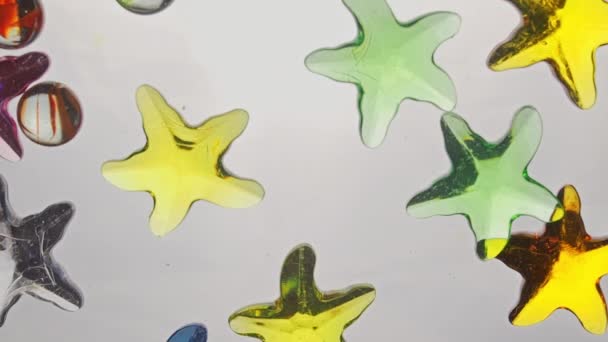 View from below as a hand pours artificial colored starfish. Background for the site, vacation. — 비디오