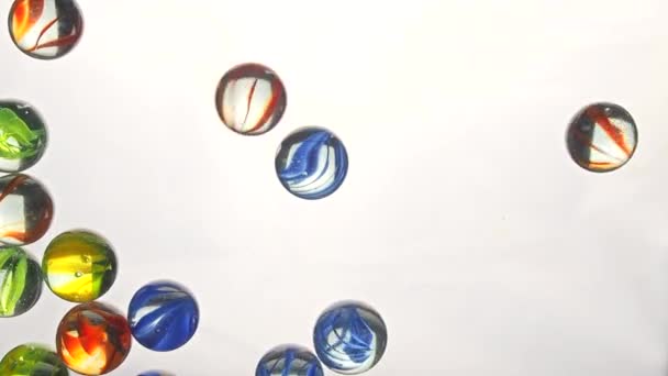 View from below as the hand throws small multi-colored colored plastic balls. White background. — Stock Video
