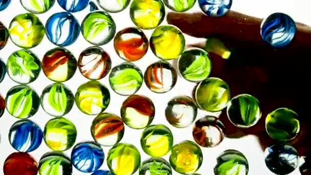 Visa underifrån när handen kastar små flerfärgade plastbollar. Vit bakgrund. — Stockvideo