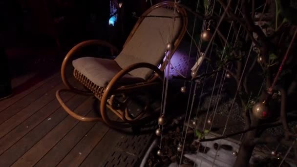 Een enkele schommelstoel staat in het felle licht. Knipperende lichten Glanzend, interieur boerenhuis, donkere kamer. — Stockvideo