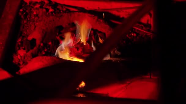 Una persona irriconoscibile che forgia una lama estrae un pezzo di metallo caldo dalla brace in fiamme . — Video Stock