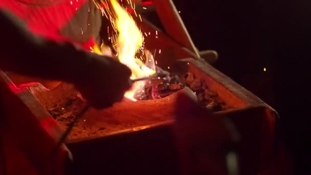 Tanımlanamayan birinin bıçak dövmesi yanan közden sıcak bir metal parçası çıkarır.. — Stok video