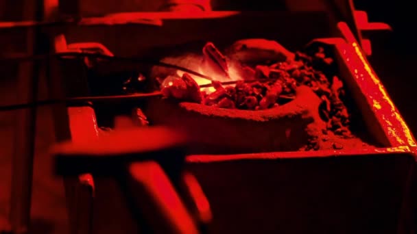 Nierozpoznawalna osoba wykuwająca ostrze wyciąga gorący kawałek metalu z płonącego żłobka.. — Wideo stockowe
