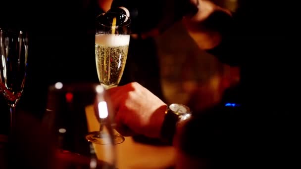 クラシックなバーテンダーは、スタイリッシュなバーの内部にあるカクテルグラスに背の高いガラスから輝くワインを注ぎます。. — ストック動画