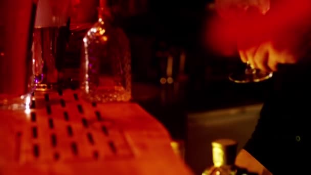 Ett klassiskt bartender häller mousserande vin från ett högt glas i ett cocktailglas i det inre av en elegant bar. — Stockvideo