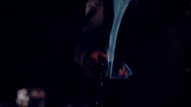 Cooking punch or grog. Adding cinnamon gives a bright flash of fire. It can be a Blue Blazer or grog.  Dark scene, close-up.