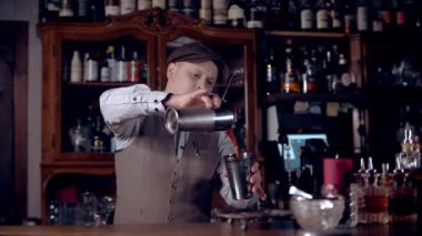 The bartender is preparing a cocktail, pouring it from a shaker into a shaker. It can be a cocktail 