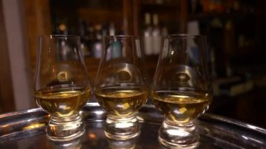 Two tasting glasses for whisky  (glencairn) with a drink on a tray, with a fixed camera. Movement around the bar.