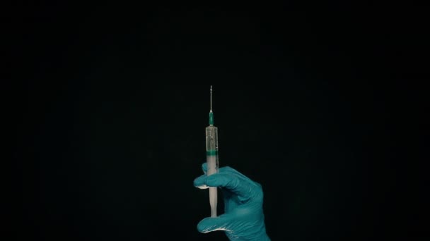 Une main dans un gant médical bleu tient une seringue injectable. Éteint les bulles d'air. Vérification de la seringue, du jet de drogue .