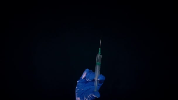 Une main dans un gant médical bleu tient une seringue injectable. Éteint les bulles d'air. Vérification de la seringue, du jet de drogue .