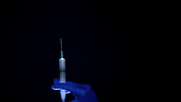 Une main dans un gant médical bleu tient une seringue injectable. Éteint les bulles d'air. Vérification de la seringue, du jet de drogue .