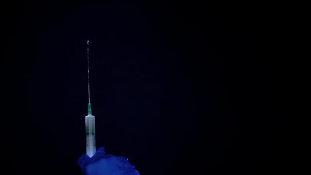 Uma mão em uma luva médica azul segura uma seringa para injeção. Abana as bolhas de ar. Verificando a seringa, o jato de drogas . — Vídeo de Stock