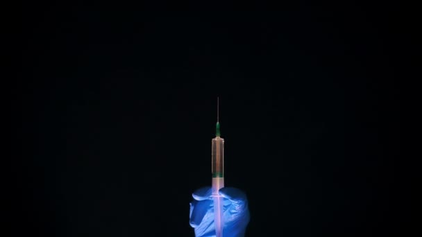 Una mano en un guante médico azul sostiene una jeringa para inyección. Sacude las burbujas de aire. Comprobando la jeringa, el chorro de droga . — Vídeos de Stock