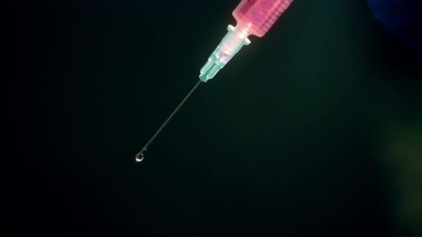 Une main dans un gant médical bleu tient une seringue injectable. Éteint les bulles d'air. Vérification de la seringue, du jet de drogue .