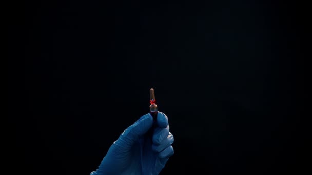 Een hand in een blauwe medische handschoen houdt een spuit voor injectie vast. Schud luchtbellen af. Controleren van de spuit, de drug jet. — Stockvideo