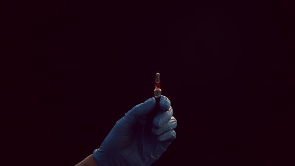 En hand i en blå medicinsk handske håller en spruta för injektion. Skakar av luftbubblor. Kontroll av sprutan, drogstrålen. — Stockvideo