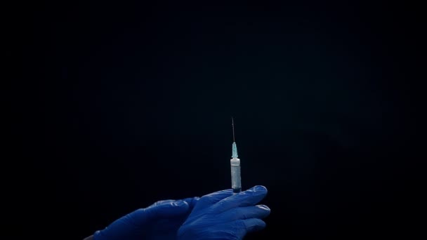 Uma mão em uma luva médica azul segura uma seringa para injeção. Abana as bolhas de ar. Verificando a seringa, o jato de drogas . — Vídeo de Stock