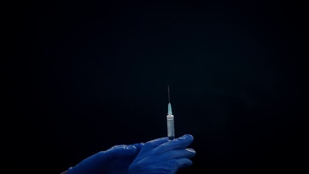 Une main dans un gant médical bleu tient une seringue injectable. Éteint les bulles d'air. Vérification de la seringue, du jet de drogue .