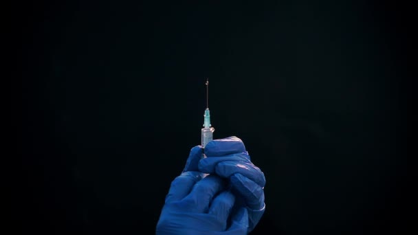 Une main dans un gant médical bleu tient une seringue injectable. Éteint les bulles d'air. Vérification de la seringue, du jet de drogue .