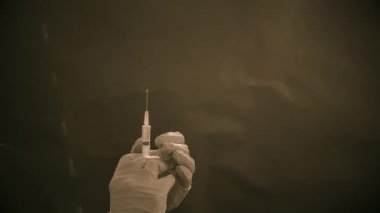 Mavi tıbbi eldivenli bir el enjeksiyon için bir şırınga tutar. Hava kabarcıklarından kurtulur. Şırıngayı ve uyuşturucu jetini kontrol ediyorum..