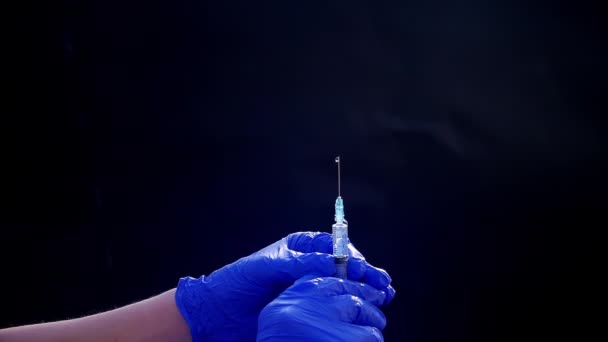 Een hand in een blauwe medische handschoen houdt een spuit voor injectie vast. Schud luchtbellen af. Controleren van de spuit, de drug jet. — Stockvideo