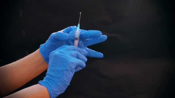 Een hand in een blauwe medische handschoen houdt een spuit voor injectie vast. Schud luchtbellen af. Controleren van de spuit, de drug jet. — Stockvideo