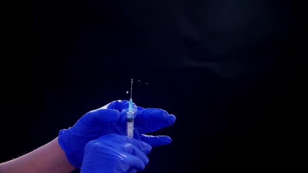 Mavi tıbbi eldivenli bir el enjeksiyon için bir şırınga tutar. Hava kabarcıklarından kurtulur. Şırıngayı ve uyuşturucu jetini kontrol ediyorum.. — Stok video